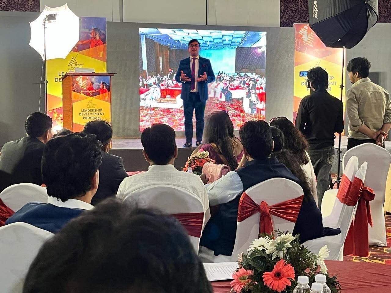 Aadesh Sharma presenting on stage at a Leadership Development Program, with the audience in the foreground