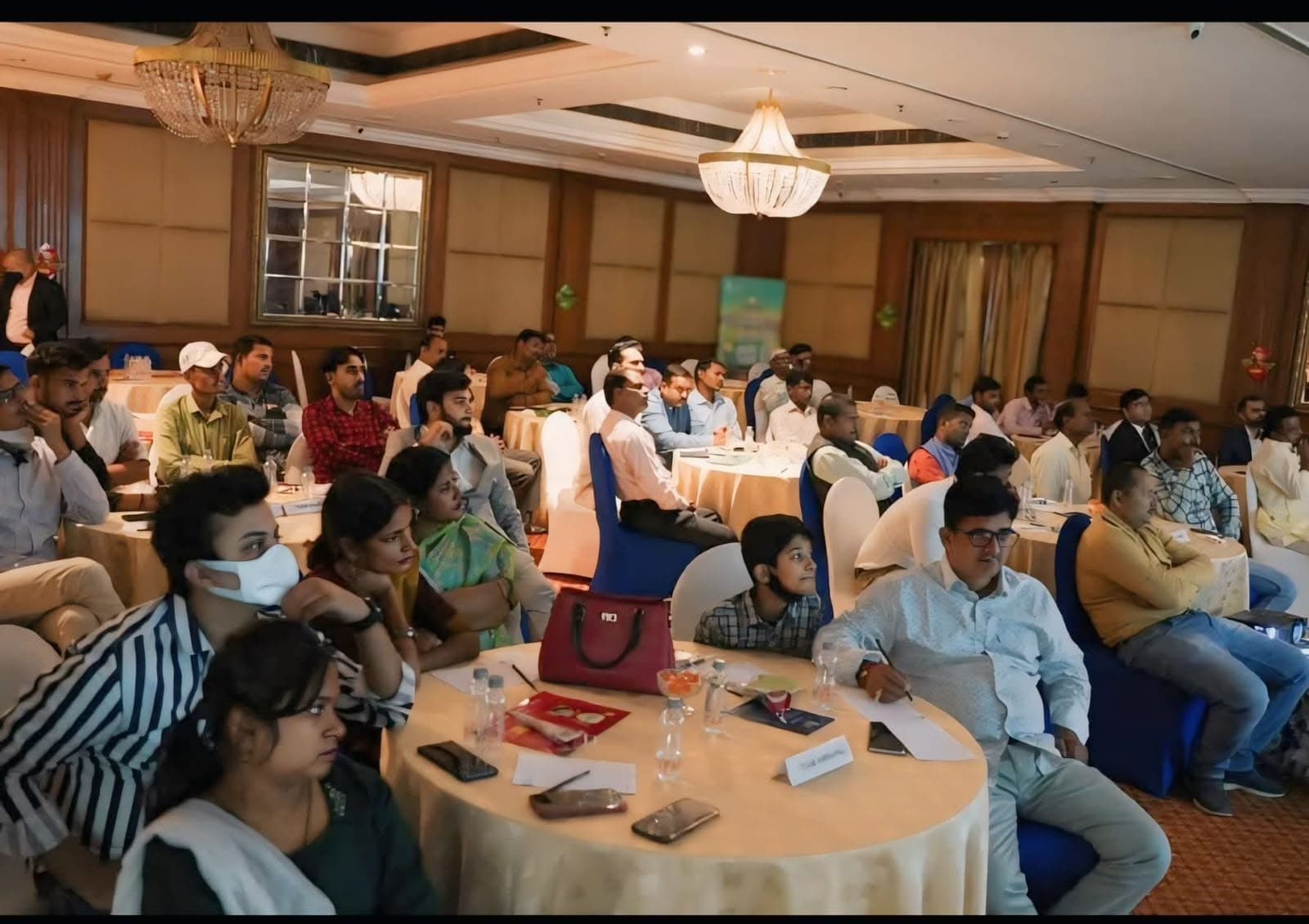 Participants seated at round tables during a workshop in a hotel ballroom